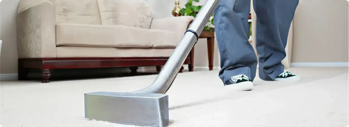 Carpet cleaning technician using a hot-water extraction wand on a light-colored carpet in a living room, Tempe, AZ.